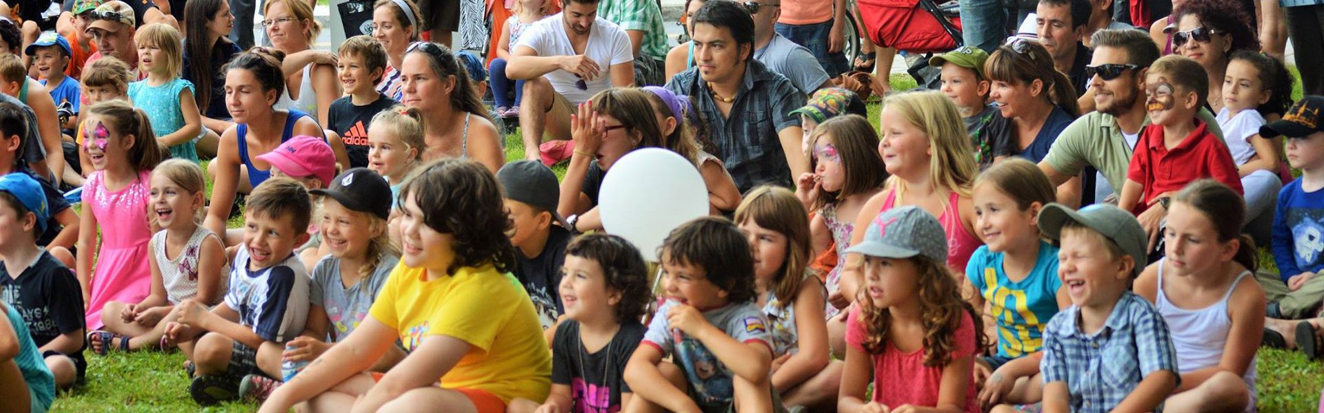 Grand groupe d'enfants et d'adultes assistant à un spectacle à l'extérieur