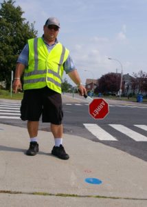 Photo du brigadier pointant le rond bleu du corridor scolaire au sol