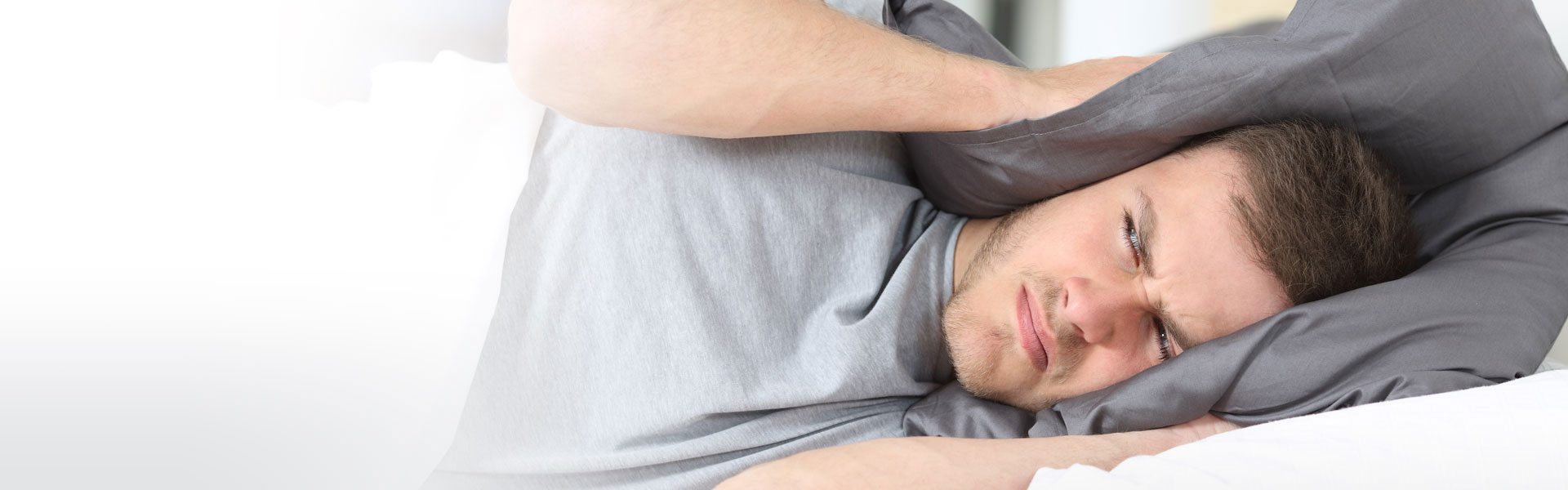 Photo d'un homme se bouchant les oreilles avec son oreiller