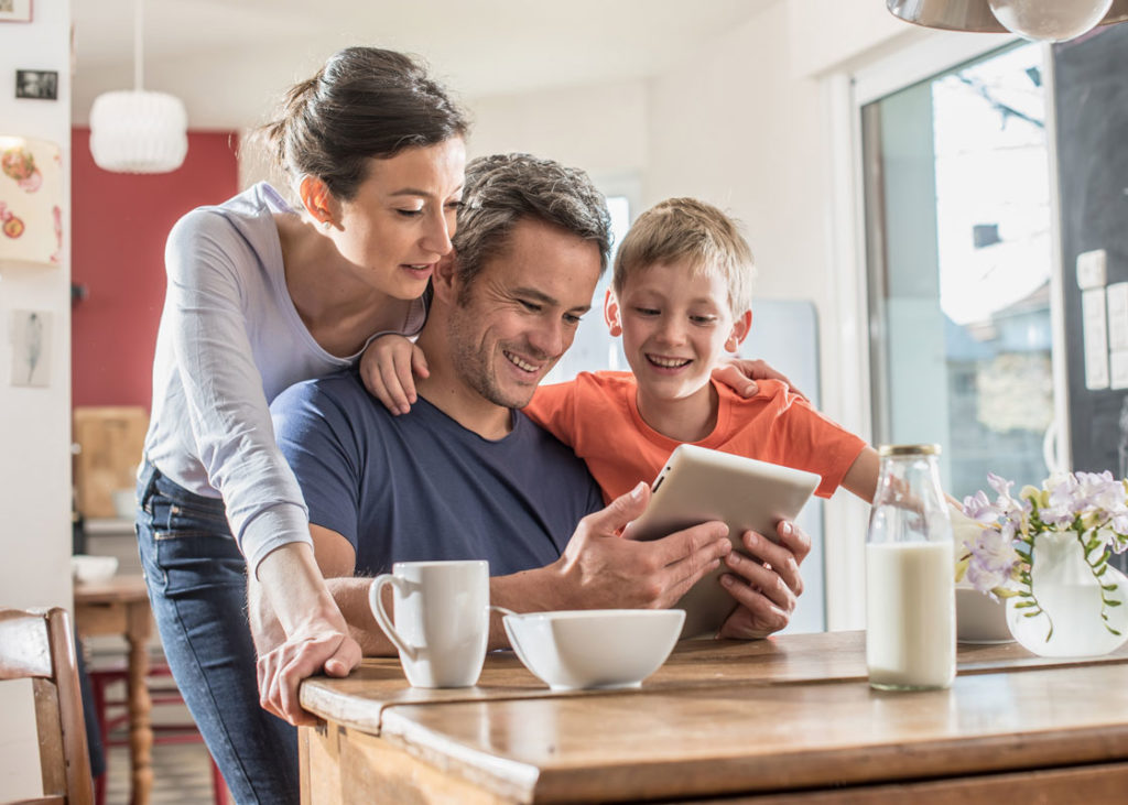 Membres d'une famille souriants en regardant une tablette